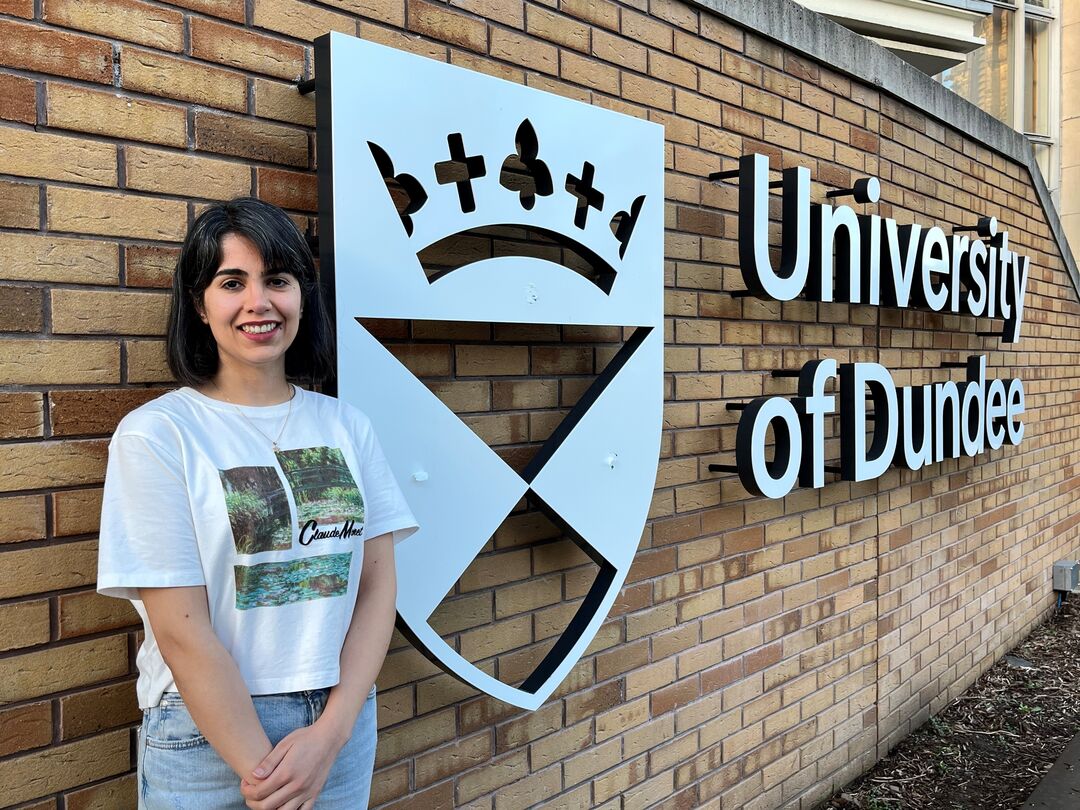 Mahtab Karami standing next to a stainless steel University of Dundee sign