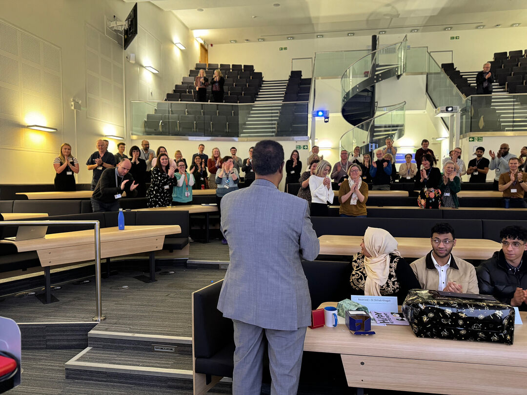 Shihab standing in the front of students in a lecture theatre