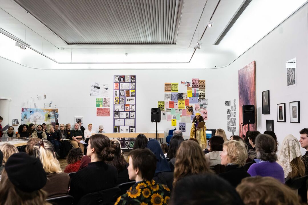 Event image. Large gathering with audience hearing from Freedom Princess, an artist dressed in gold