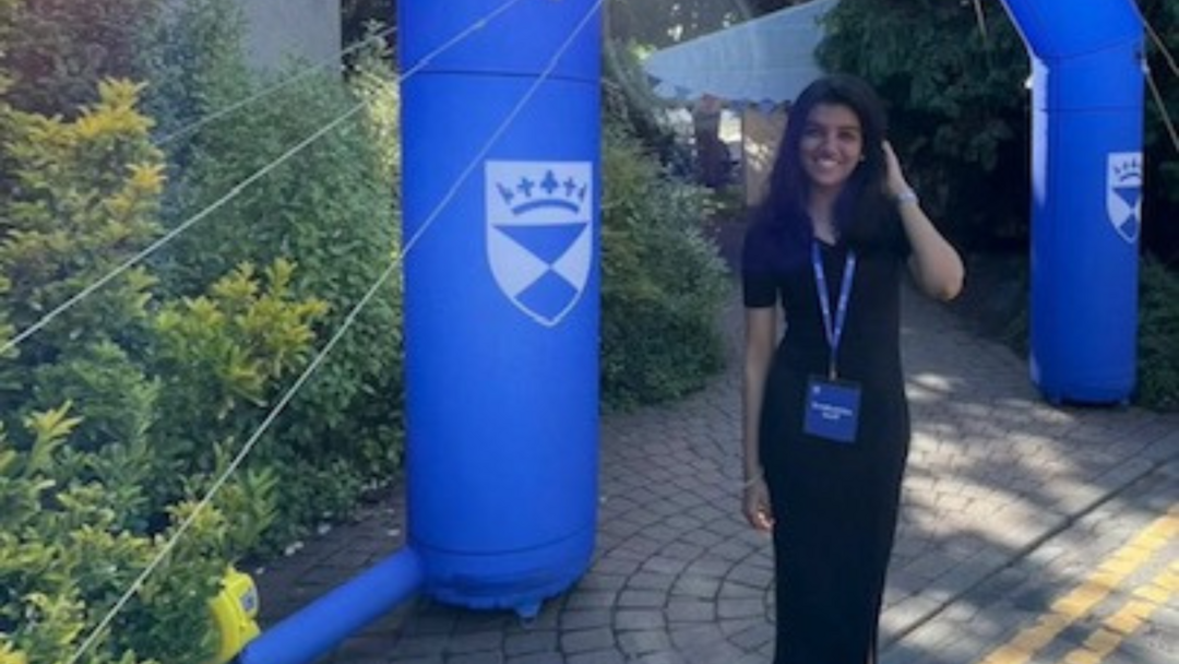 A person stands next to a blue inflatable with a white University of Dundee shield logo on it.