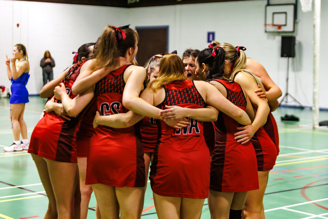 A group of people in the same red strip are huddling together.