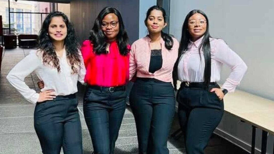 Four girls stand in a line  with their arms around each other
