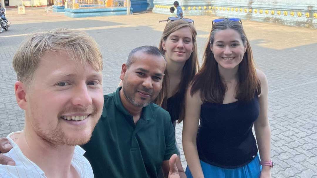 Four people stand together, looking towards the camera and smiling.