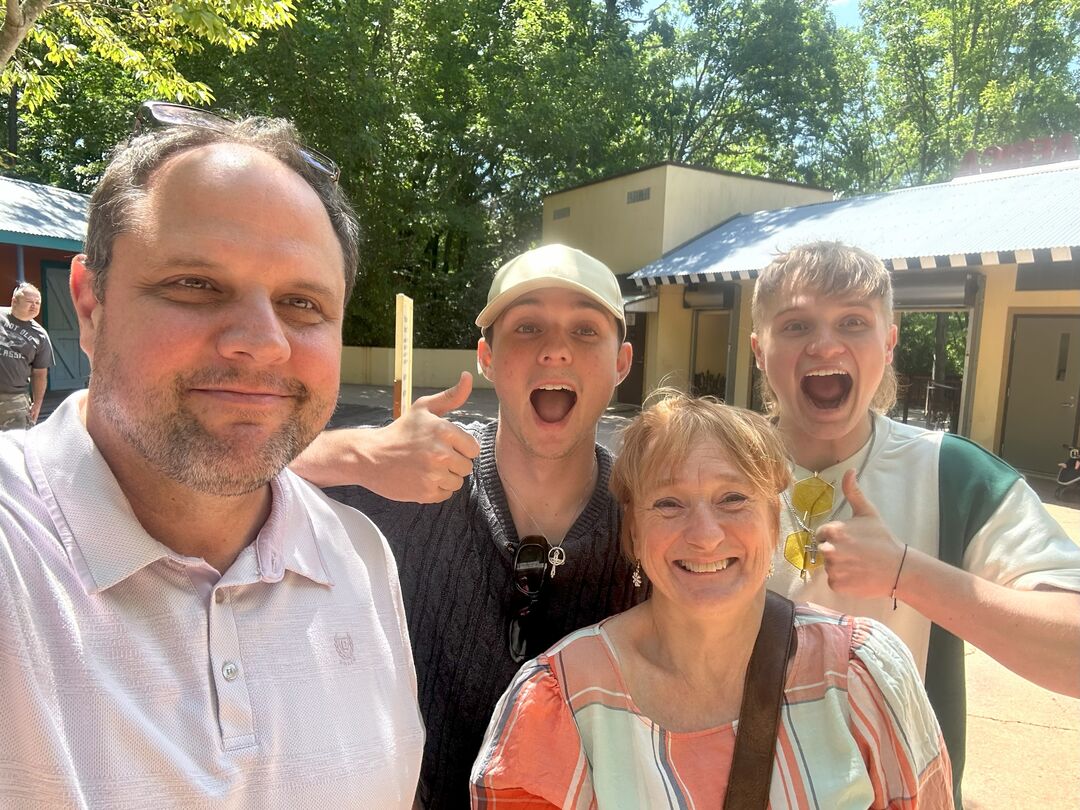 A man and woman stand smiling with two younger men standing behind them.