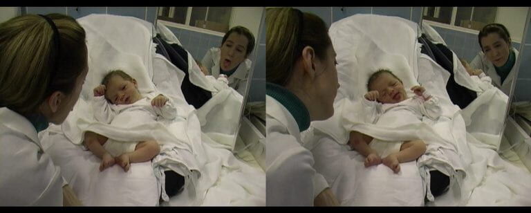 A person smiling at a baby in a cot