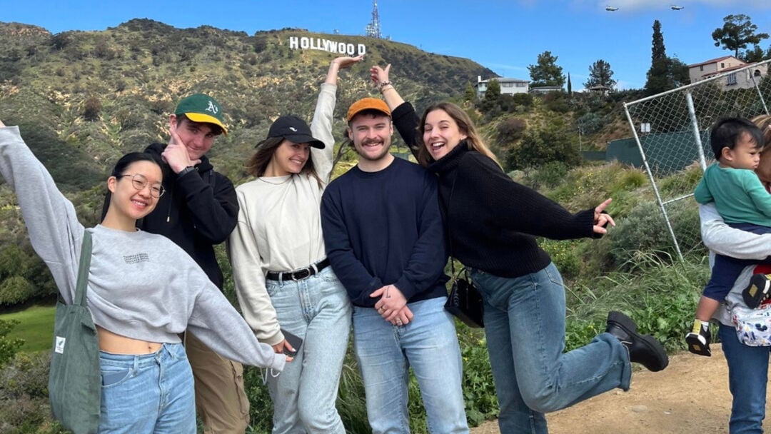 A group of 5 students, smiling and posing for the camera, with the Hollywood sign and hills in the background