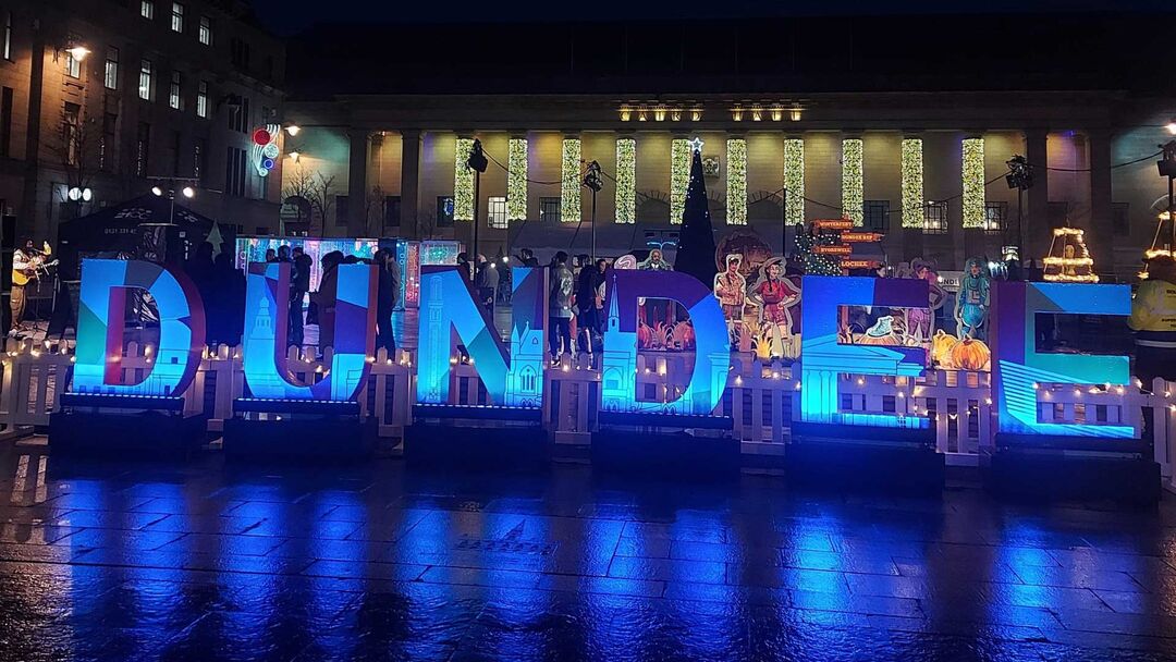 Dundee sign light up in darkness at night time in front of the Caird Hall in Dundee City centre.