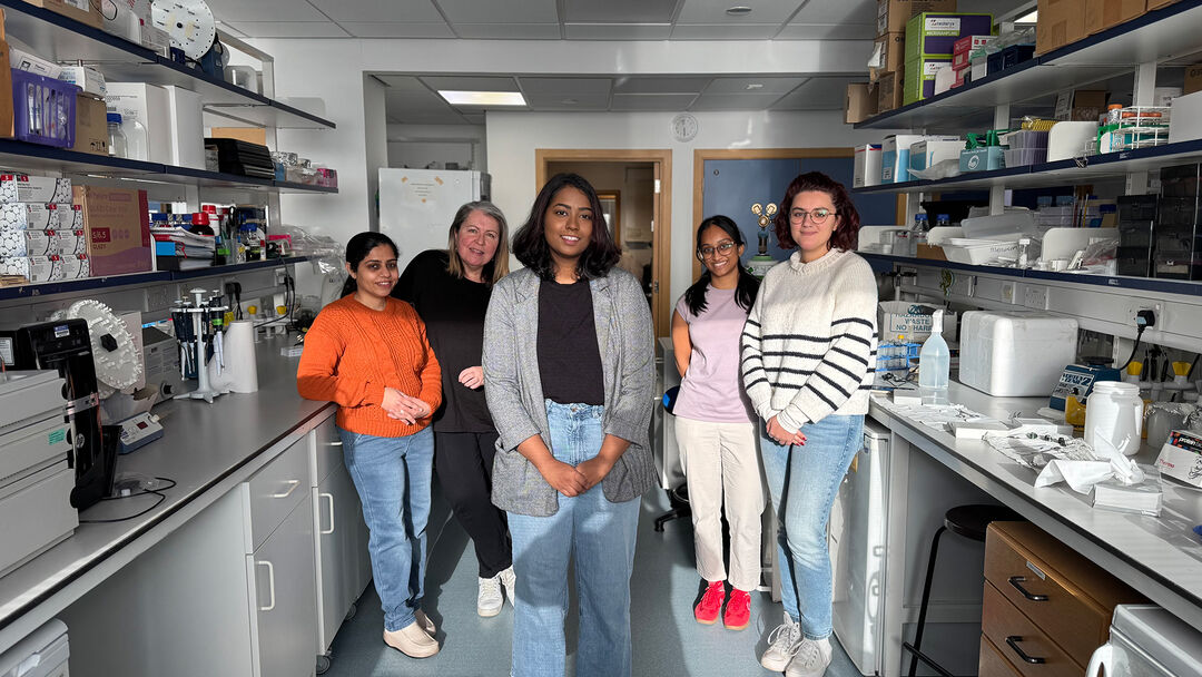 Group of researchers pose for group photo next to laboratory benches