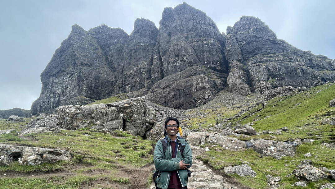 Student smiling with hills and a big rock in the background.
