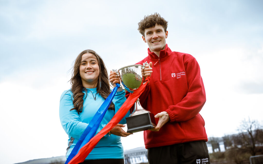 young man and woman both holding a trophy 