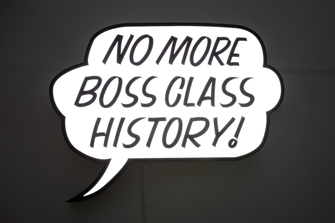 Lightbox sculpture in the shape of a comic speech bubble reading 'no more boss class history!'