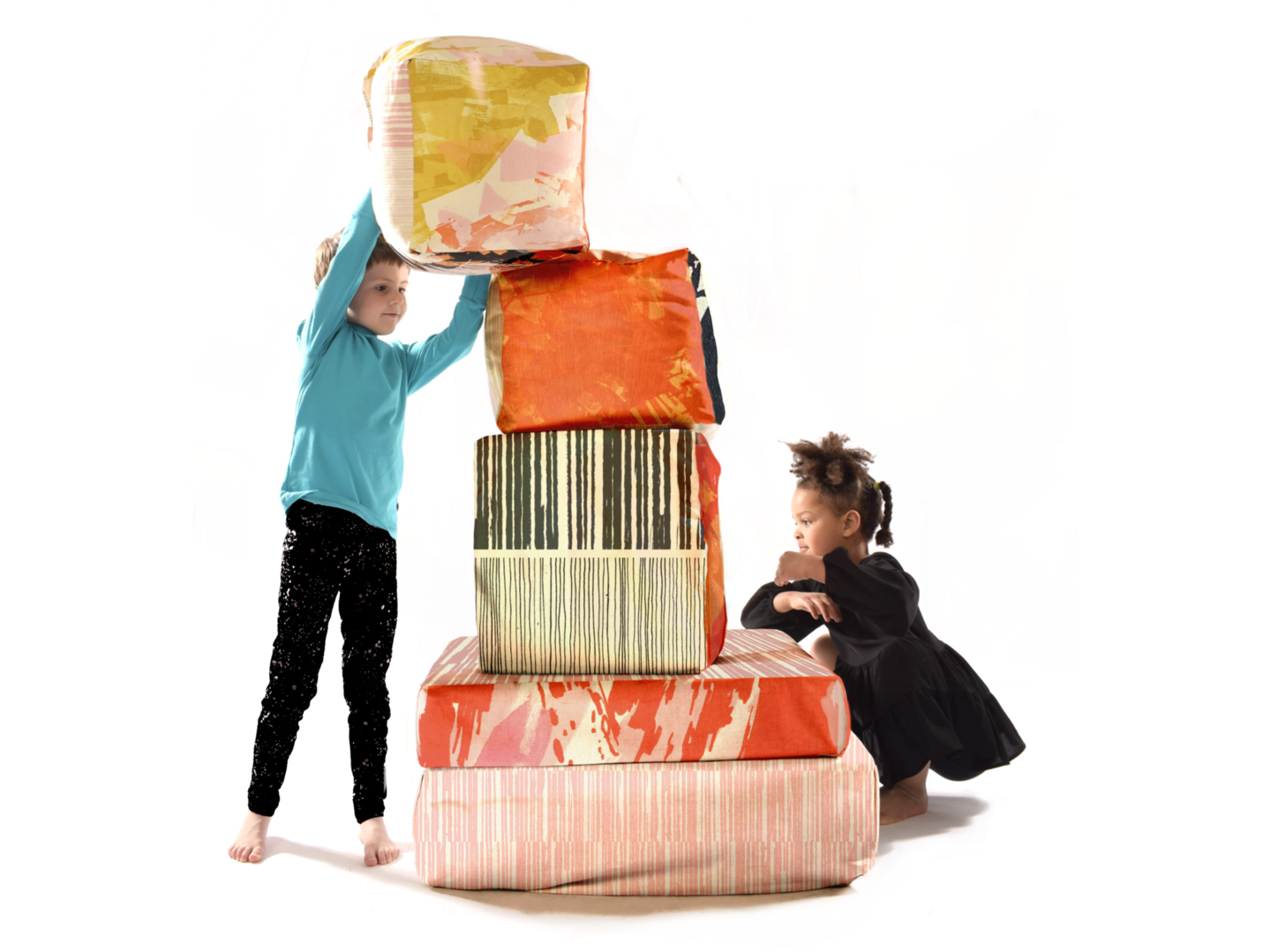 Two children play with the textile cubes, stacking them up.